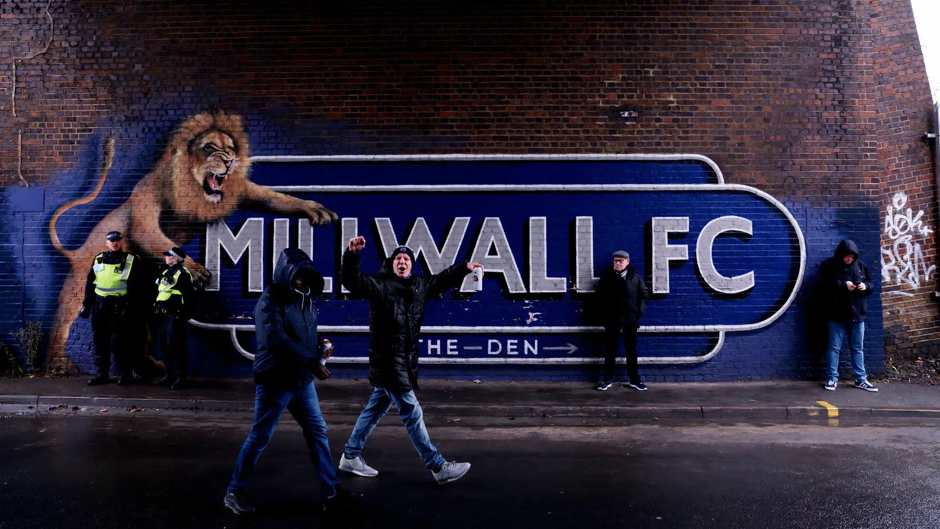 Cổ động viên Millwall cuồng nhiệt và gây áp lực cho đối thủ tại The Den, thể hiện văn hóa cổ động mạnh mẽ và bầu không khí gây thù địch